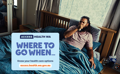 Man with the flu laying in bed coughing into a tissue. 