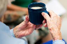 Elderly person's hands holding cup of tea.