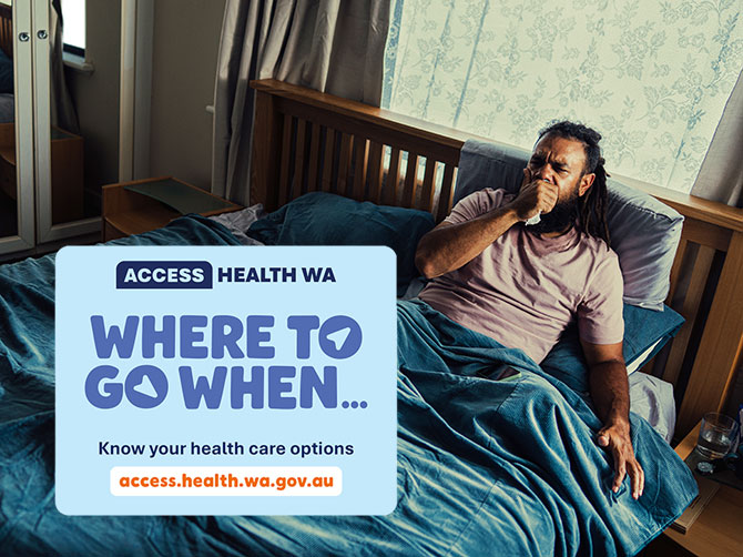 Man with the flu laying in bed coughing into a tissue. 