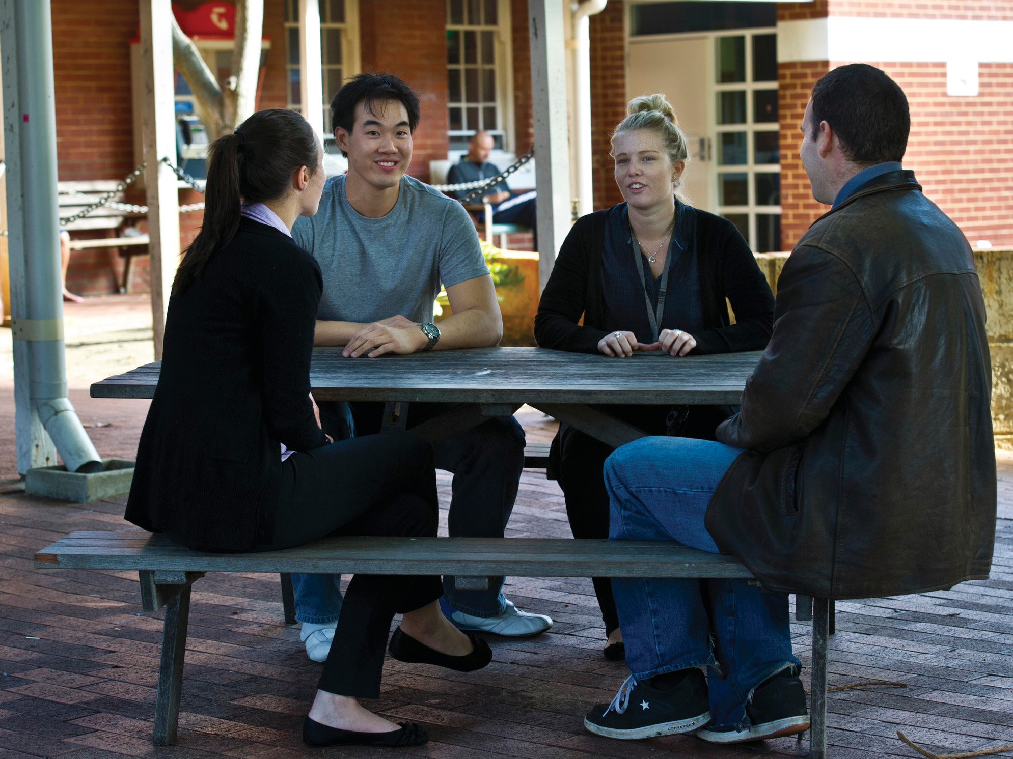 4 people sitting around a picnic table talking