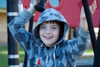 Boy wearing hooded jumper playing in playground