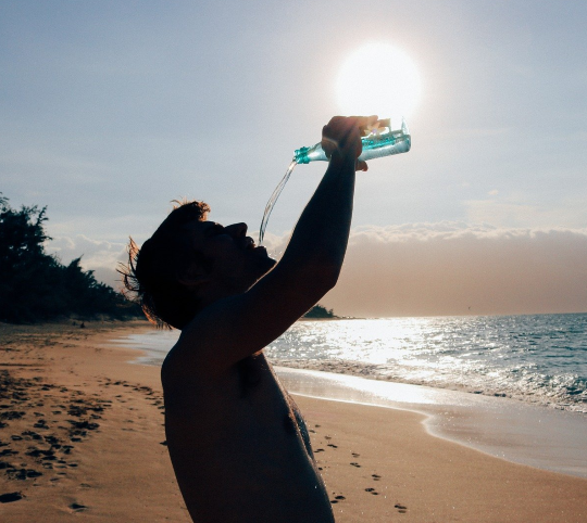 Man drinking a bottle of water at the beach