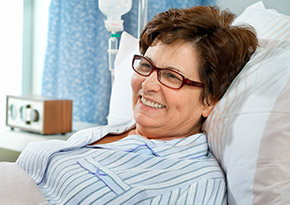 Woman lying in a hospital bed wearing a gown