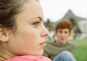 Teen aged girl and boy sitting outside on the grass