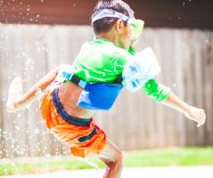 Boy wearing floaties doing bomby in pool