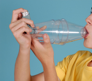 Person using ventolin inhaler with large volume spacer