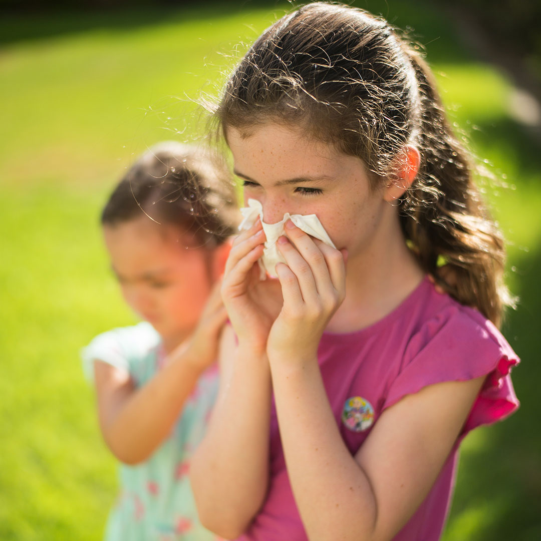 Young girl in park blowing her nose