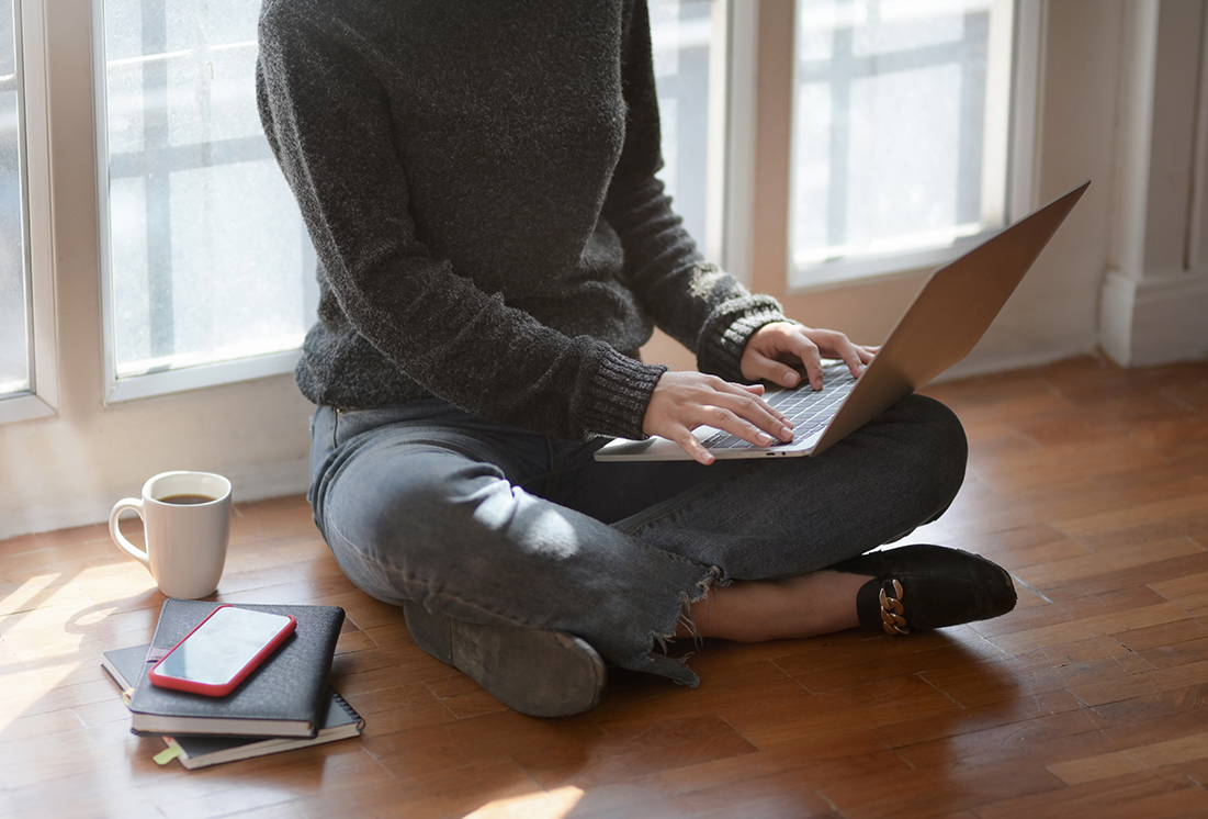 woman sitting cross-legged on the floor using her laptop